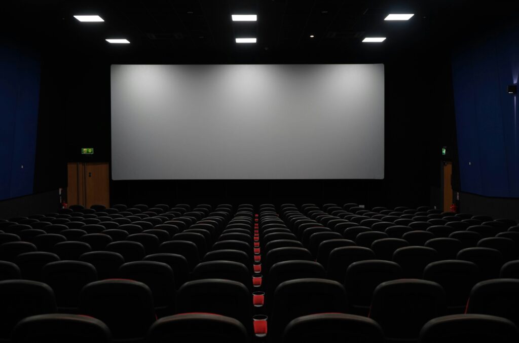 Blick in einen Kinosaal mit grosser leerer Leinwand. 